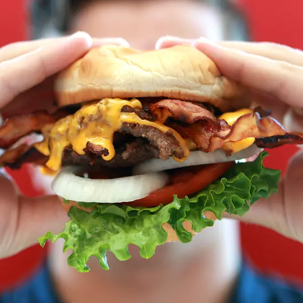 Steakburger fait maison à base de viande, d’oignon, de salade, de tomates et de fromage.